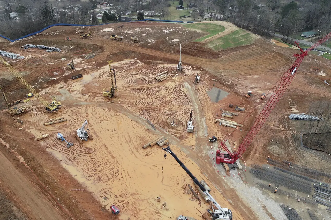 Aerial view of an active civil works site with cranes and piling rigs