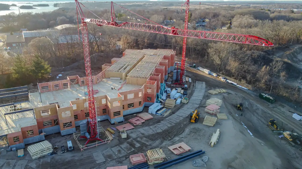 Aerial view of a building under construction with two red tower cranes