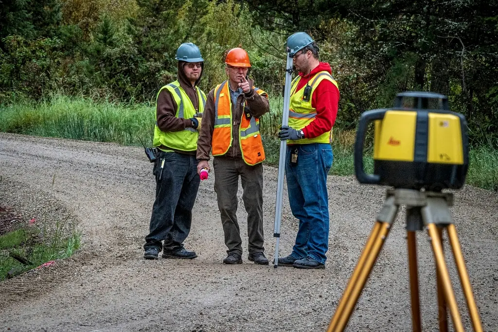 Land surveyors with a levelling rod and rotating laser level